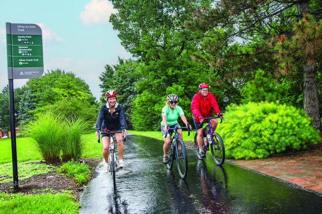 Three cyclists riding along a tree-lined Westerville bike trail